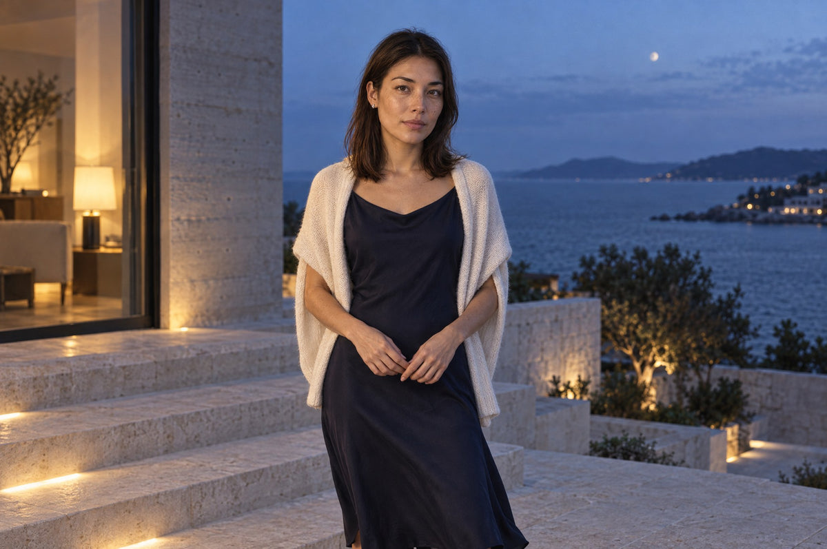 A woman in a long fluid midnight dress stands on limestone steps at blue hour and looks into the camera